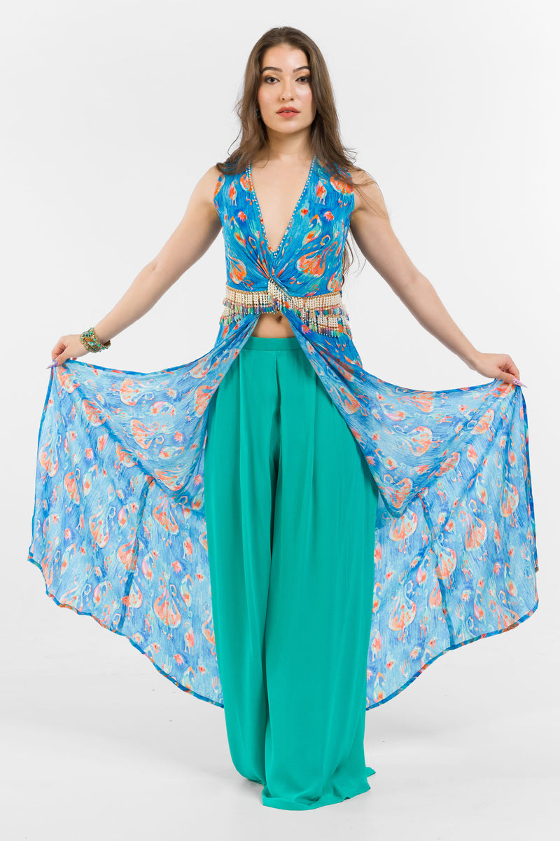 A PRINTED TUNIC WITH A PLUNGE NECKLINE AND SIDE CUT OUT DETAIL, WORN OVER PALLAZO PANTS